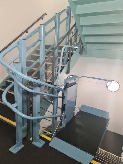 The stairlift platform features a sturdy base, plus a foldable seat for non-wheelchair users.